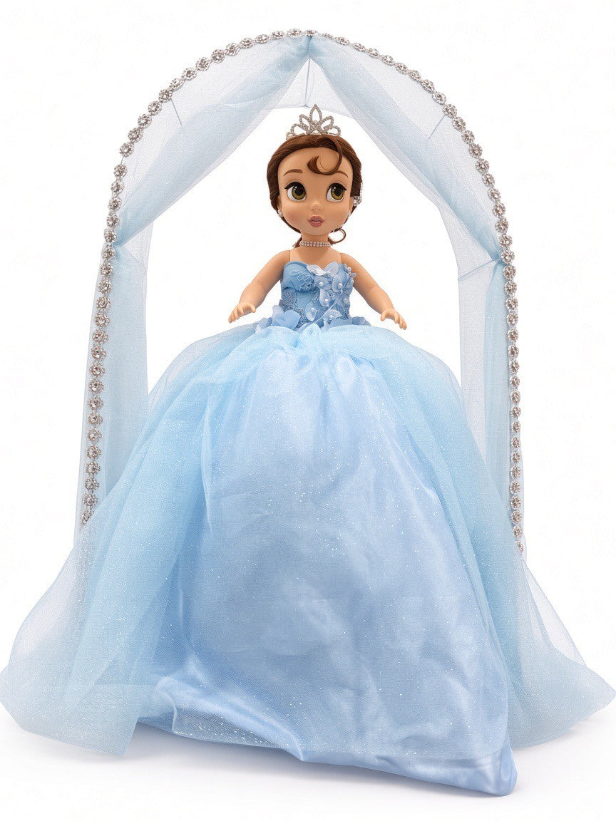 Blue última muñeca front view – doll in light blue glitter ball gown with tiara under a blue tulle arch