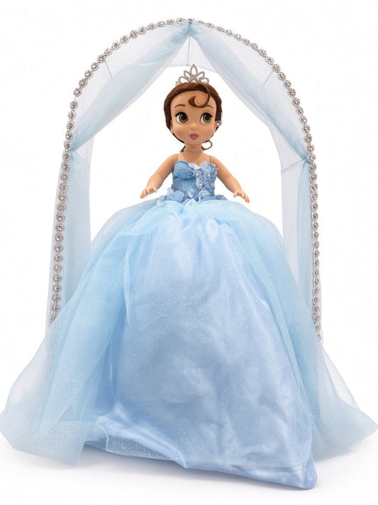 Blue última muñeca front view – doll in light blue glitter ball gown with tiara under a blue tulle arch